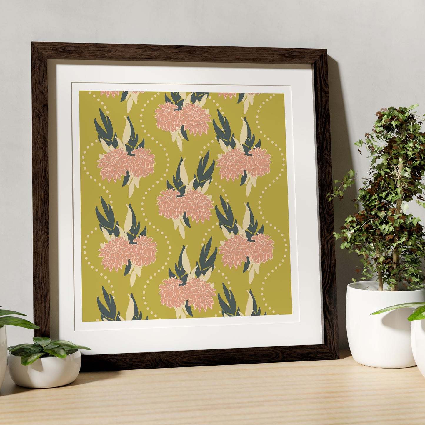 Framed floral artwork on a wooden table with plants