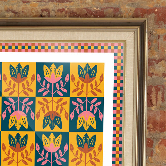 Framed colorful pattern on a brick wall with a blue sofa and yellow vase.