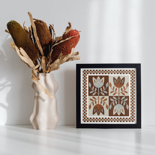 Framed 432 Design artwork with floral design next to a vase with dried plants on a white surface