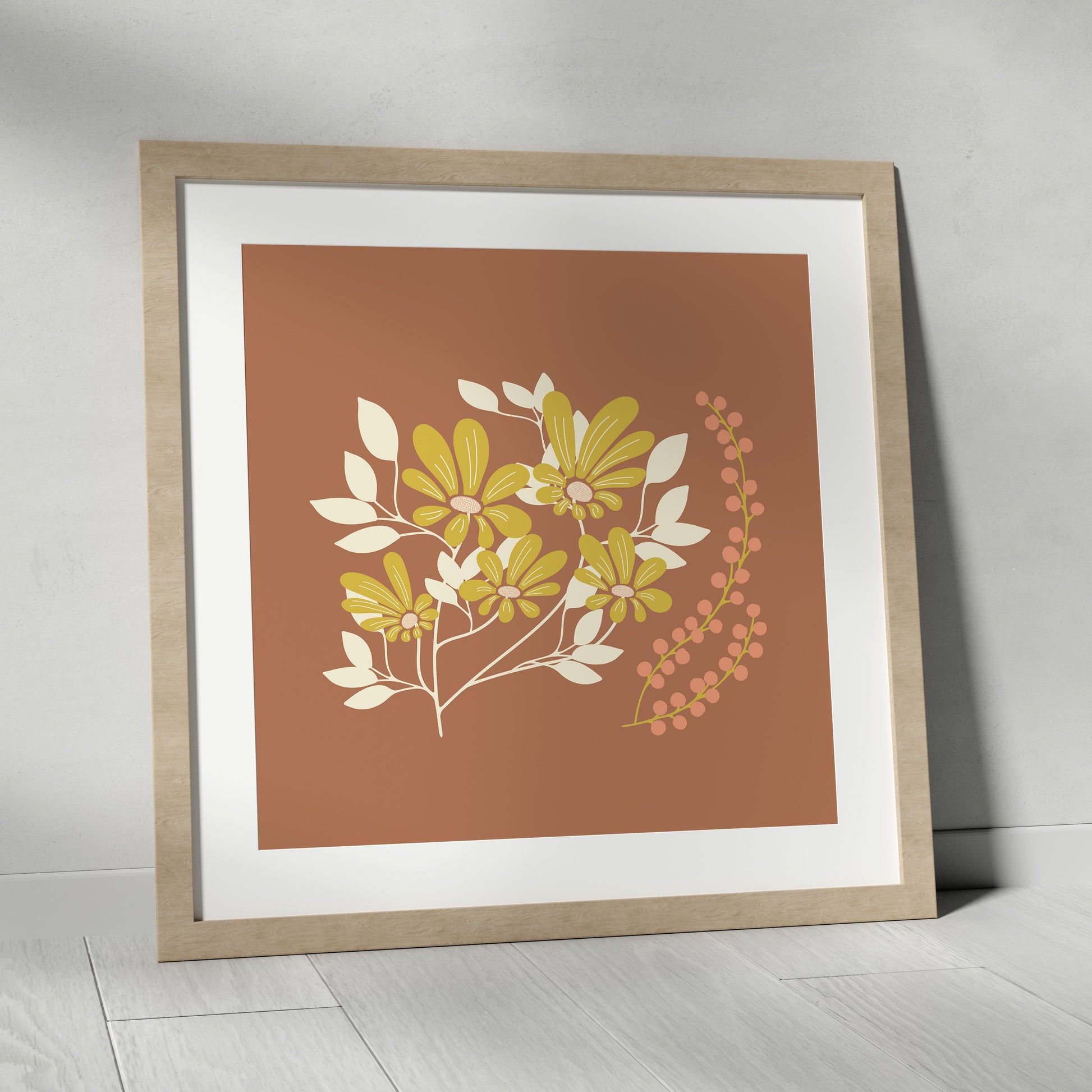 Framed artwork with floral design on a brown background, placed on a light wooden floor.
