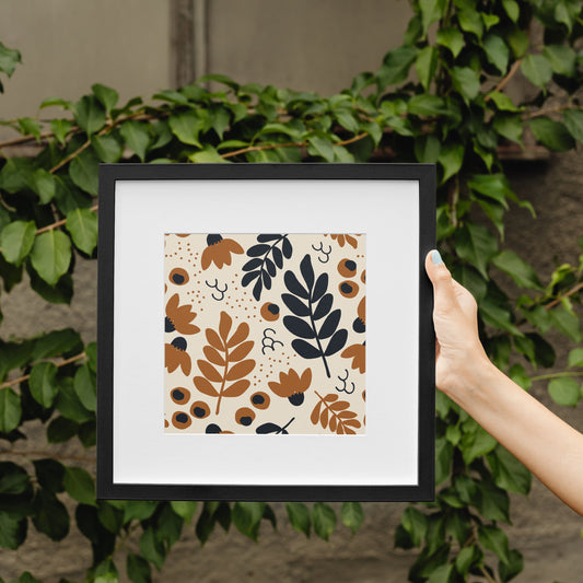 Framed artwork with leaf pattern held by a hand against a green leafy background